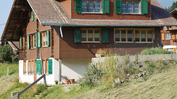 A two-story house with a sloped roof, green shutters, and a stone foundation. - Gehret Appartement/Fewo, Dusche, WC, 1 Schlafraum 2-Zimmerwohnung by Interhome (Adelboden)