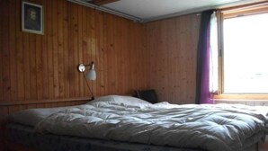 A single bed with a white duvet in a room with wooden walls and a window with purple curtains. - Gehret Appartement/Fewo, Dusche, WC, 1 Schlafraum 2-Zimmerwohnung by Interhome (Adelboden)