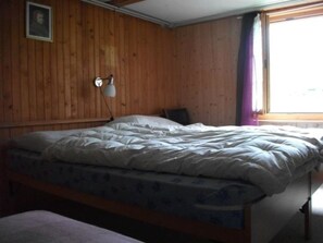 A single bed with a white duvet in a room with wooden walls and a window with purple curtains. - Gehret Appartement/Fewo, Dusche, WC, 1 Schlafraum 2-Zimmerwohnung by Interhome (Adelboden)