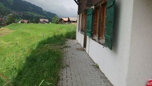 A pathway leading to a building with a sloped roof and green shutters. - Gehret Appartement/Fewo, Dusche, WC, 1 Schlafraum 2-Zimmerwohnung by Interhome (Adelboden)