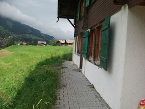 A pathway leading to a building with a sloped roof and green shutters. - Gehret Appartement/Fewo, Dusche, WC, 1 Schlafraum 2-Zimmerwohnung by Interhome (Adelboden)