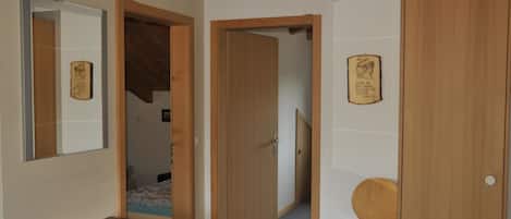 A room with a wooden dresser, a chair, and a door leading to another room.