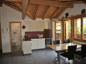 A modern kitchen with wooden beams, a central island, and a dining area with chairs.