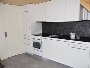 Eine moderne Küche mit weißen Schränken, einer schwarzen Arbeitsplatte, einem Edelstahl-Spülbecken und einem Backofen.