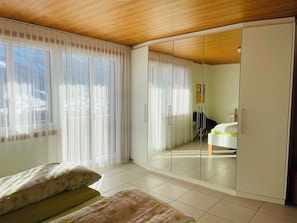 A bedroom with a bed, a wardrobe, and a mirror. - Juwel 2 Appartement/Fewo, Bad, WC, 2 Schlafräume 3.5-Zimmerwohnung by Interhome (Adelboden)