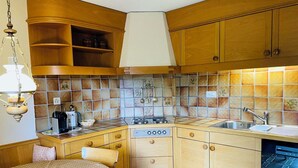 Una cucina compatta con mobili in legno, un piano cottura a gas, un lavello e un'area pranzo con tavolo e sedie.
