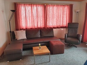 A living room with a sofa, a chair, a coffee table, and a floor lamp. - Walt-Elis Appartement/Fewo, Bad, WC, 2 Schlafräume 3-Zimmerwohnung by Interhome (Adelboden)