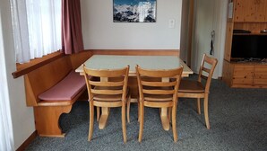 Una habitación con una mesa y sillas de madera, un banco, un cuadro en la pared y un aparador de madera.