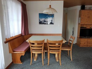 A room with a wooden table and chairs, a bench, a painting on the wall, and a wooden cabinet. - Walt-Elis Appartement/Fewo, Bad, WC, 2 Schlafräume 3-Zimmerwohnung by Interhome (Adelboden)