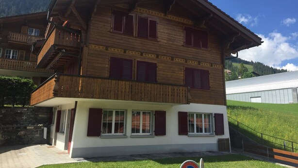Un edificio de madera de varios pisos con balcones, ventanas amplias y una pared de piedra.