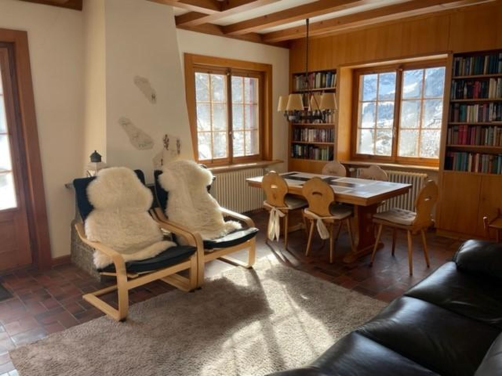 Una sala de estar acogedora con chimenea, una mesa de comedor con sillas y una estantería llena de libros.