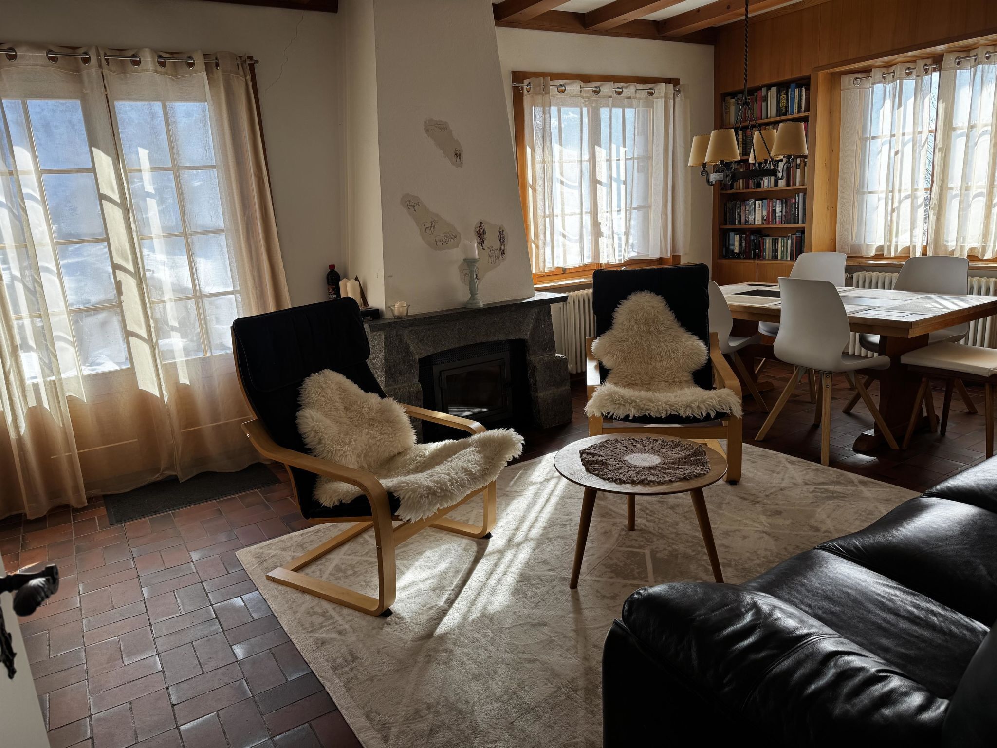 Ein Wohnzimmer mit Kamin, zwei Sesseln, einem Couchtisch und einem Essbereich mit Stühlen und Tisch.