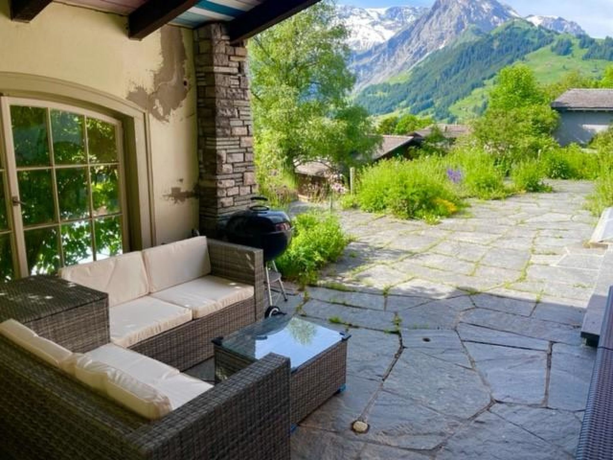 A patio with wicker furniture, a stone floor, and a mountain view.