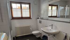 Un baño con inodoro, lavamanos, radiador y ventana con persianas.