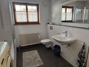 A bathroom with a toilet, sink, radiator, and a window with blinds. - Baslerdybli Appartement/Fewo, Bad, WC, 3 Schlafräume 4-Zimmerwohnung by Interhome (Adelboden)