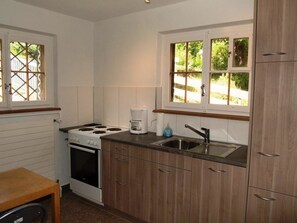 A compact kitchen with a stove, sink, and wooden cabinets. - Baslerdybli Appartement/Fewo, Bad, WC, 3 Schlafräume 4-Zimmerwohnung by Interhome (Adelboden)