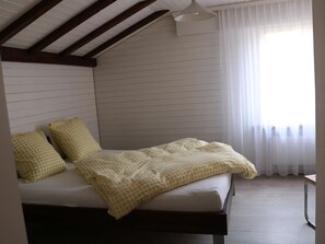 A bedroom with a bed, pillows, a window with curtains, and a ceiling fan. - Rapunzel AP D22 Appartement/Fewo, Bad, WC, 2 Schlafräume 3-Zimmerwohnung by Interhome (Adelboden)