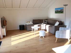 A modern living room with a wooden floor, a grey sofa, a white armchair, and a small white table. - Rapunzel AP D22 Appartement/Fewo, Bad, WC, 2 Schlafräume 3-Zimmerwohnung by Interhome (Adelboden)