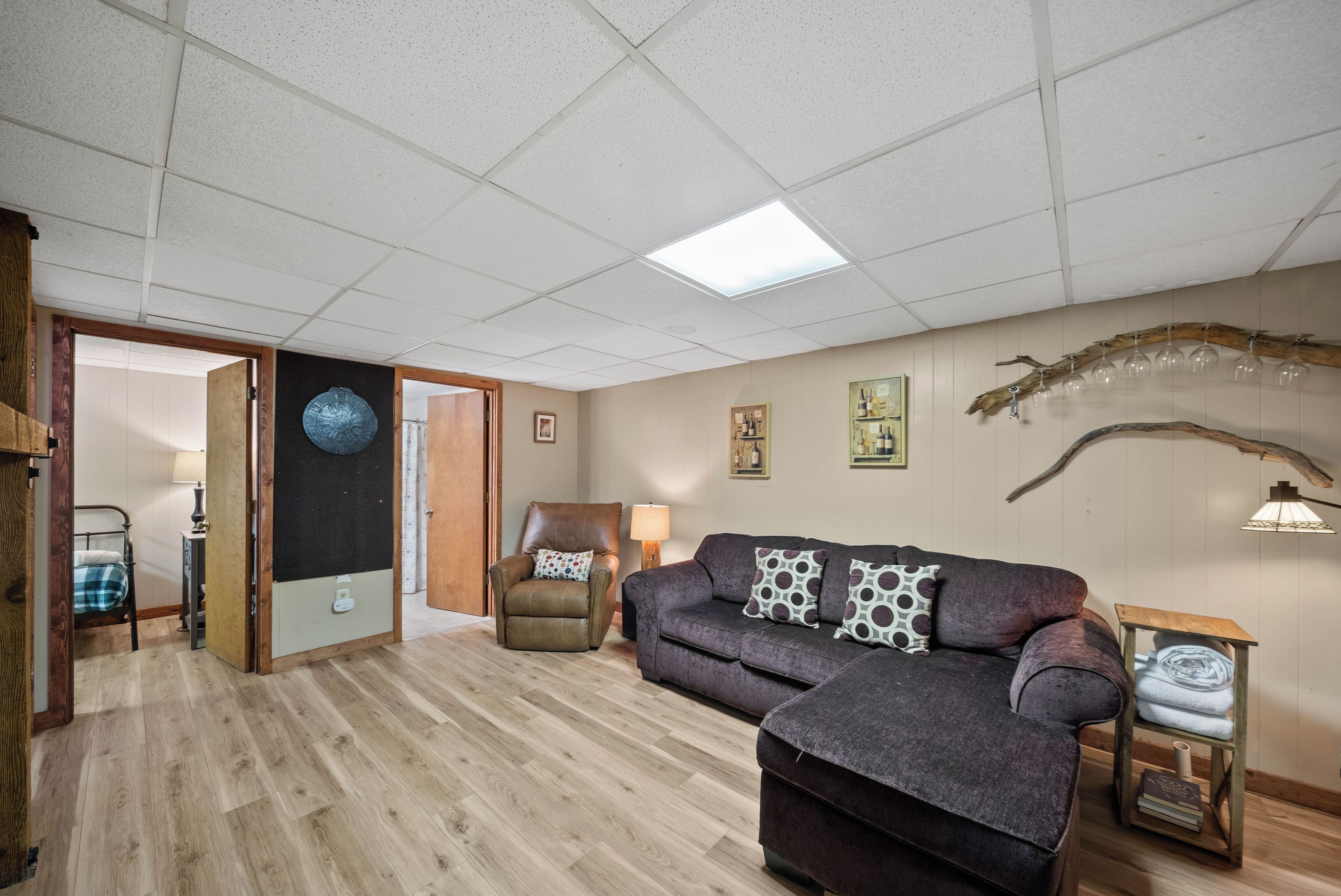 A living room with a sofa, armchair, and a coffee table. There is a door leading to another room.