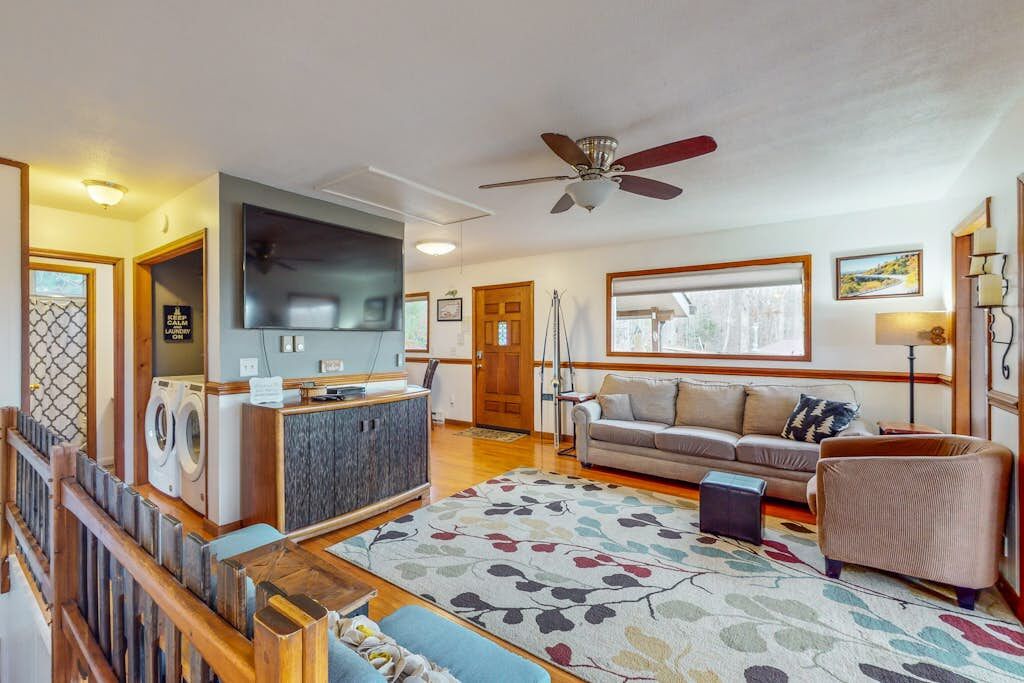 A living room with a sofa, a television, a ceiling fan, and a washing machine.