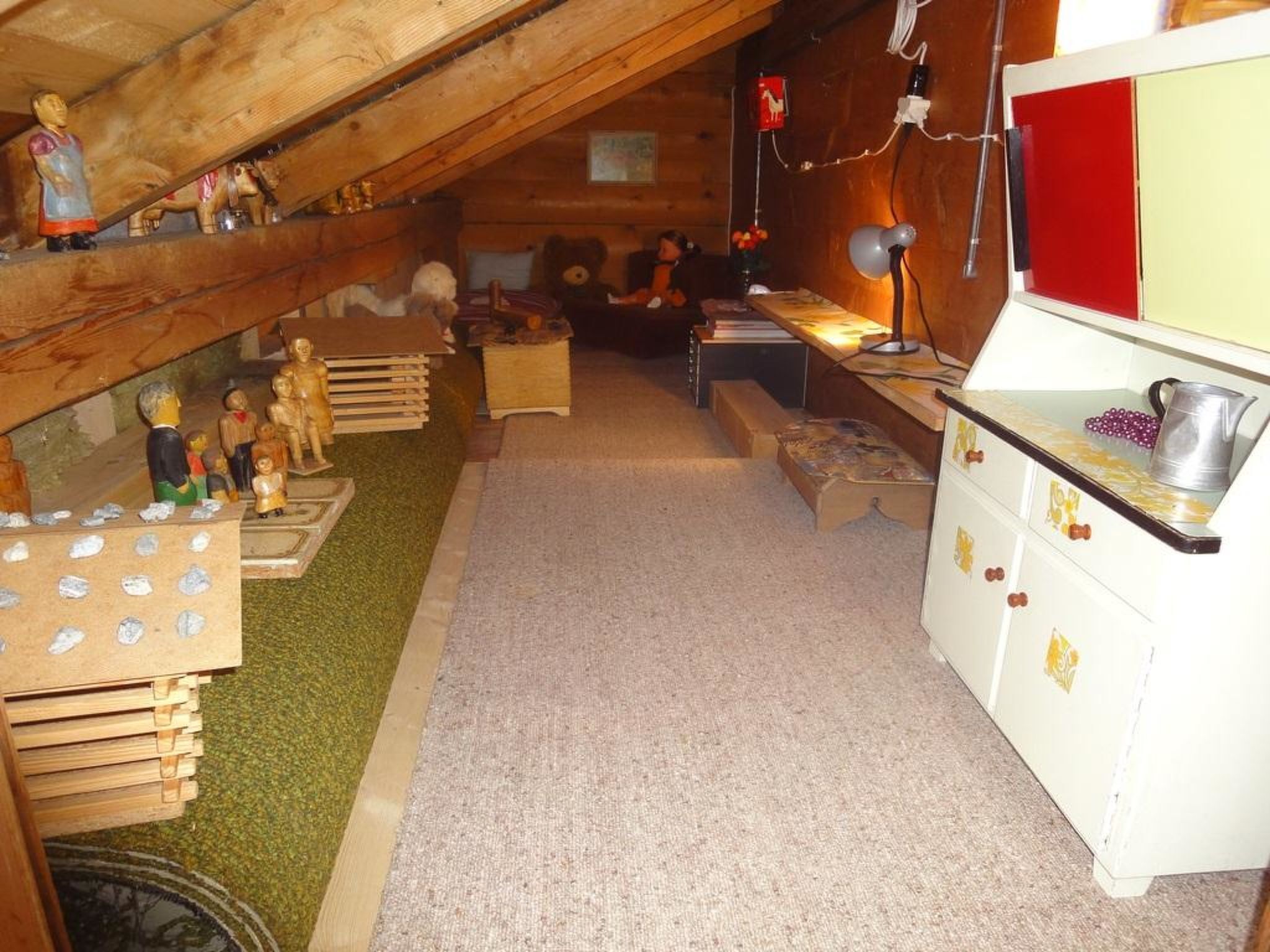 Une petite pièce mansardée avec des poutres en bois, un coin cuisine et un lit en mezzanine.