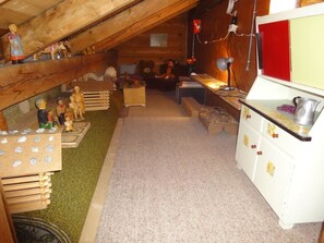 Una habitación pequeña en el ático con vigas de madera, una kitchenette y una cama entrepiso.