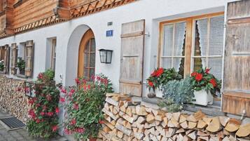 Un bâtiment traditionnel avec une façade blanche, des volets en bois et un mur en pierre.