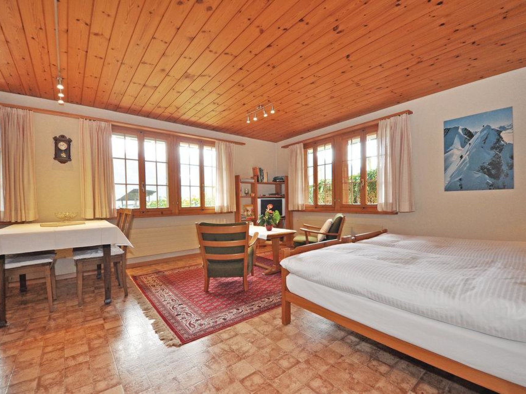Une pièce avec un plafond en bois, un lit, un bureau avec des chaises et une bibliothèque.