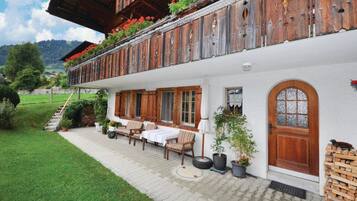 Un chalet traditionnel doté d’une terrasse, de volets en bois et d’un jardin.