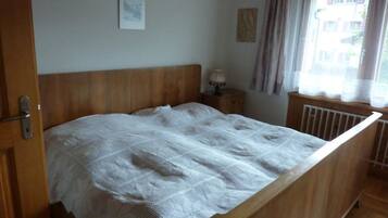 Une chambre à coucher avec un lit en bois, une table de chevet, une lampe et une fenêtre avec des rideaux.