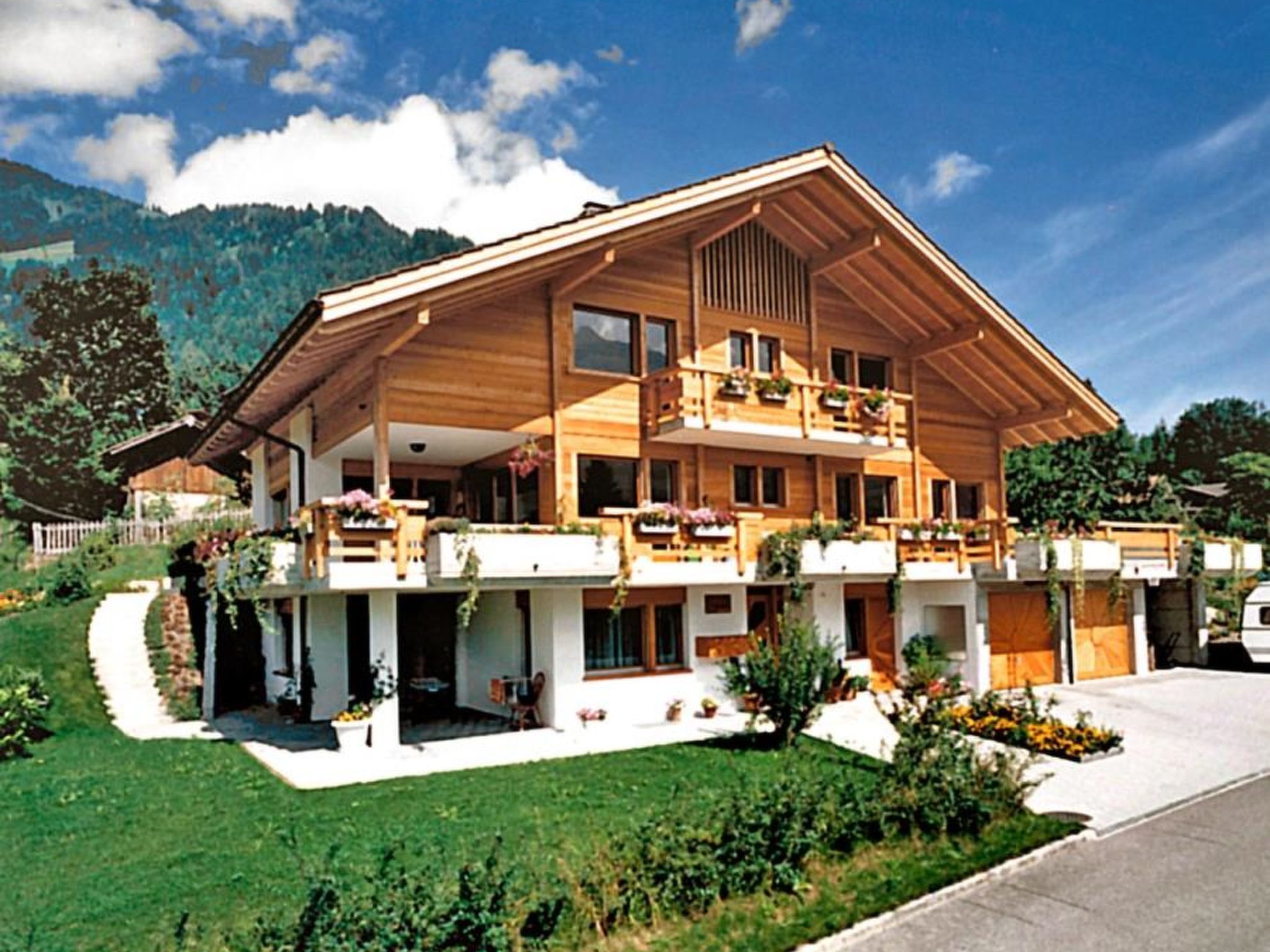 Un chalet en bois à deux étages, doté de balcons, entouré d’un jardin bien entretenu et avec une vue sur les montagnes.