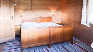 A wooden room with a bed, a nightstand, and a wall-mounted light fixture. - Weidhütte Wegscheide Hütte, Dusche, WC, 3 Schlafräume Wohnung 1. Stock by Interhome (Frutigen)