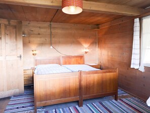 Ein Zimmer aus Holz mit einem Bett, einem Nachttisch und einer Wandleuchte.