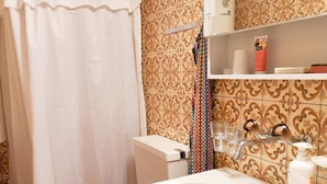 A bathroom with a white sink, a toilet, a shower curtain, and a shelf with toiletries. - Weidhütte Wegscheide Hütte, Dusche, WC, 3 Schlafräume Wohnung 1. Stock by Interhome (Frutigen)