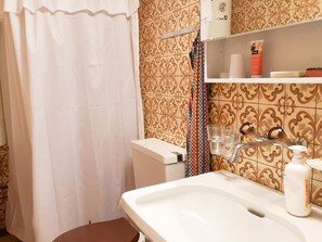 Ein Badezimmer mit weißem Waschbecken, Toilette, Duschvorhang und Ablage für Toilettenartikel.
