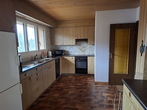 Eine Küche mit Holzausstattung, einem schwarzen Backofen und einer gefliesten Spritzschutzwand.
