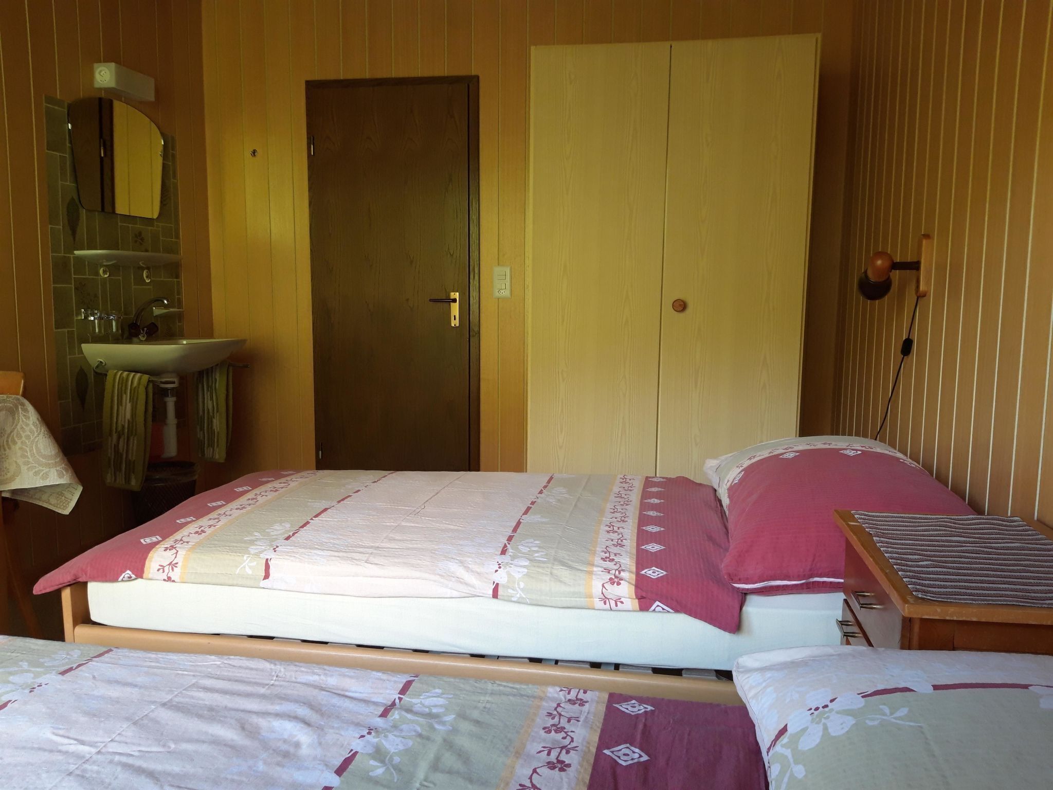 Une chambre à coucher avec un lit, une table de chevet, un miroir et une armoire.