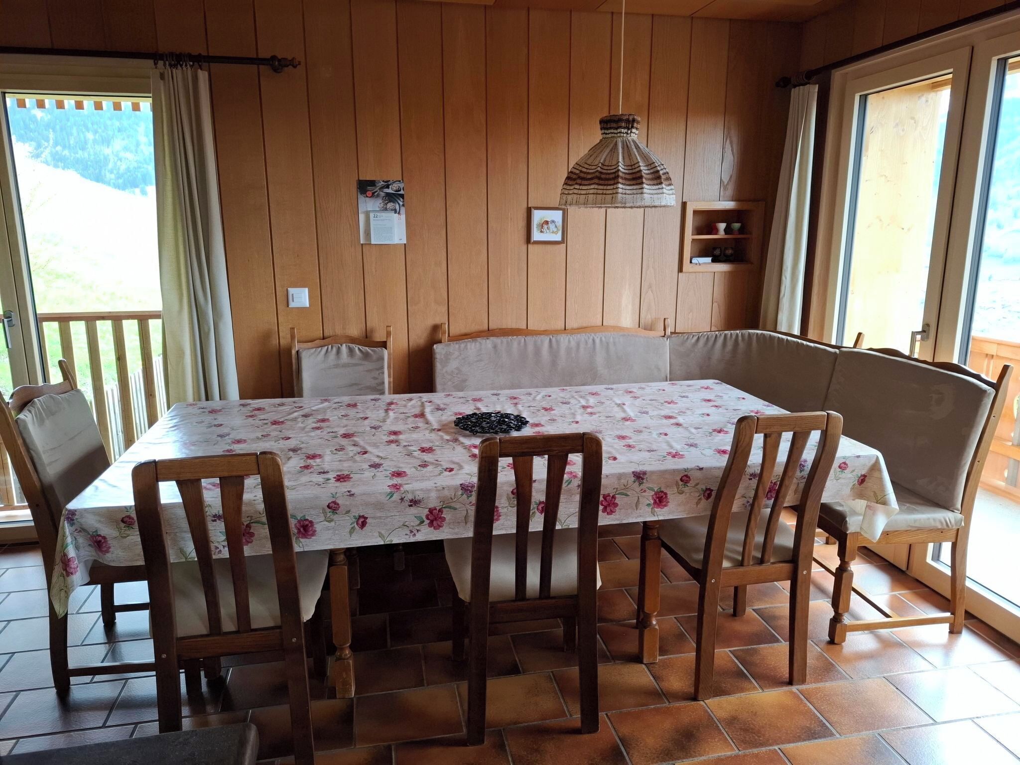 Comedor con mesa dispuesta para seis personas, sillas de madera, un banco e iluminación colgante.