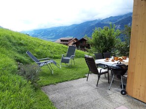 Ein Sitzbereich im Freien mit Stühlen und Tisch, mit Blick auf eine Berglandschaft.