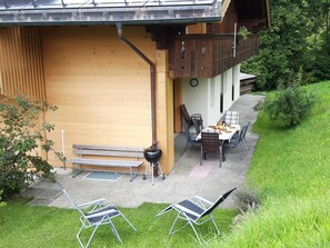 Une terrasse avec une table et des chaises, un banc et un barbecue.