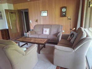 A living room with a sofa set, a coffee table, and a wall-mounted clock. - Chalet Wenger Appartement/Fewo, Dusche und Bad, WC, Balkon by Interhome (Reichenbach)