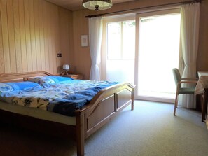 Un dormitorio con una cama de madera, una mesita de noche, una silla y una ventana con cortinas.