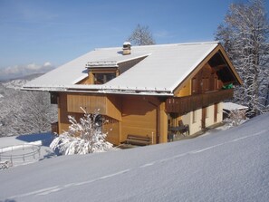 A wooden chalet with a sloped roof, a chimney, and a balcony overlooking a snowy landscape. - Chalet Wenger Appartement/Fewo, Dusche und Bad, WC, Balkon by Interhome (Reichenbach)