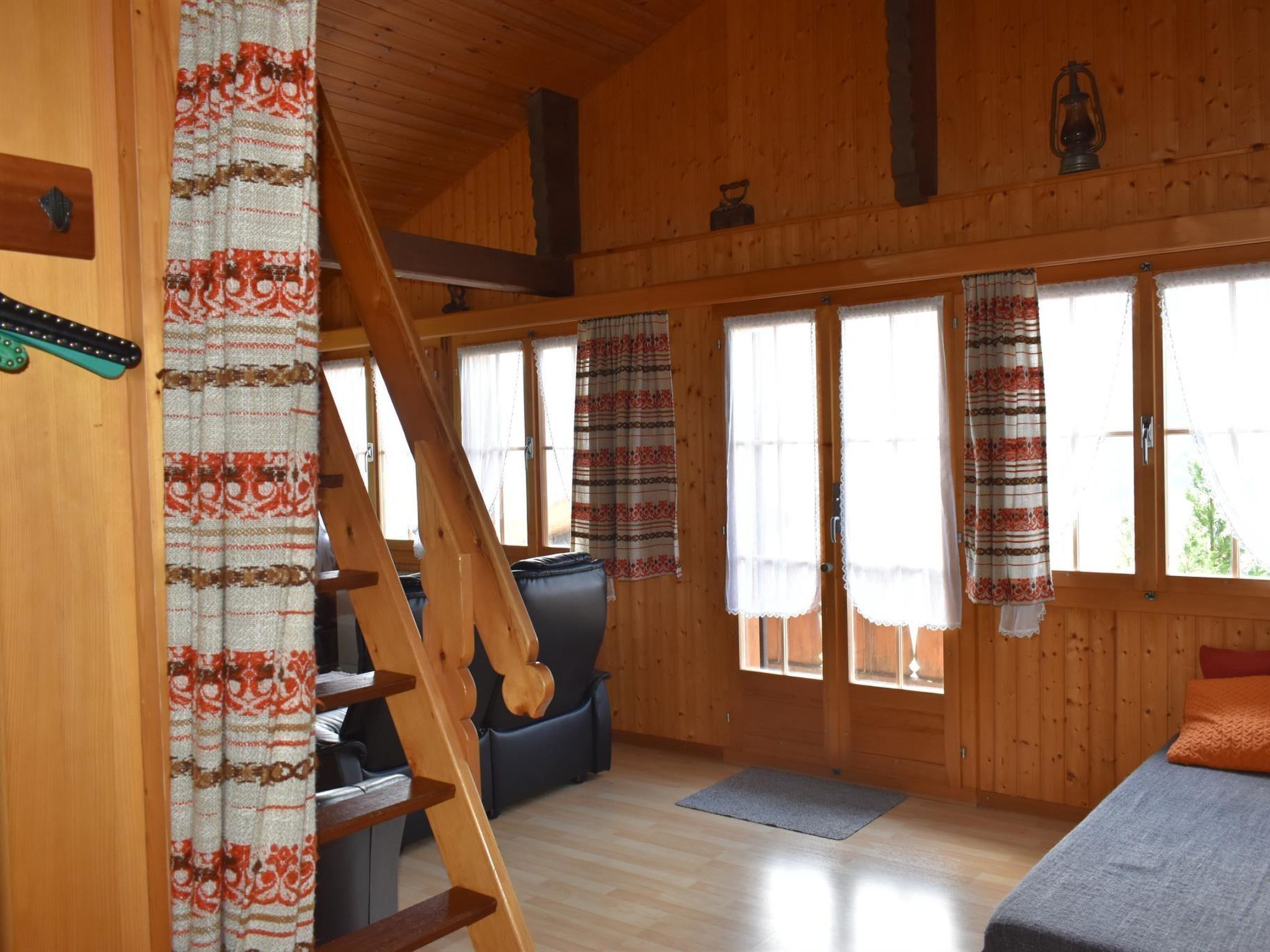 A wooden interior with a staircase, a sofa, and a bed.