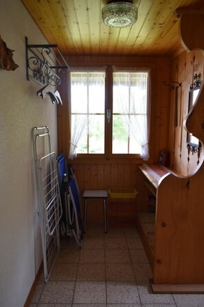 A compact kitchen with a window, a small stool, and a metal rack. - Chalet Niesenblick Appartement/Fewo, Bad, WC, 2 Schlafräume 3-Zimmerwohnung by Interhome (Reichenbach)