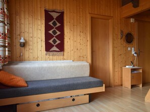 Ein Zimmer mit Holzwänden, einer Couch, einer Wandlampe und einer kleinen Holzkabine.
