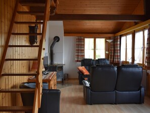 A cozy cabin interior with a wooden staircase, a fireplace, a sofa set, and a dining area. - Chalet Niesenblick Appartement/Fewo, Bad, WC, 2 Schlafräume 3-Zimmerwohnung by Interhome (Reichenbach)
