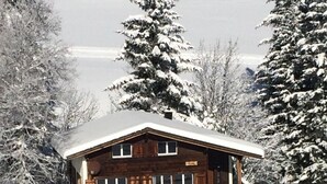 A wooden cabin with a snow-covered roof, surrounded by snow-laden trees, and a ski lift in the background. - Schalmi Appartement/Fewo, Dusche, WC, 2 Schlafräume 3-Zimmerwohnung DG by Interhome (Adelboden)