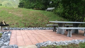 An outdoor patio area with stone tables and benches, surrounded by a low stone wall. - Schalmi Appartement/Fewo, Dusche, WC, 2 Schlafräume 3-Zimmerwohnung DG by Interhome (Adelboden)