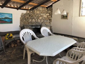 A stone fireplace with a white table and chairs in a rustic setting. - Sunnegruess UG Appartement/Fewo, Dusche, WC 1.5 Zimmerwohnung by Interhome (Adelboden)